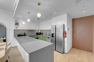 a kitchen with a refrigerator and a counter top at Gym, Spa & Sauna, Pool, Tenis Court, Dishwasher, 2BR in Central Park in Dubai
