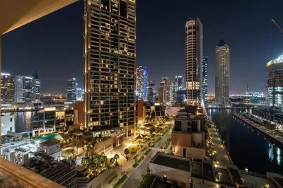 a view of a city at night with buildings at Modern 1BR Canal View Pool View in Dubai