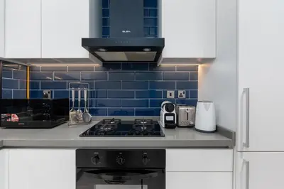a kitchen with a stove and a blue tiled wall at Luxury 2BR Business Bay Balcony in Dubai