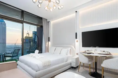 a bedroom with a white bed and a table and a large window at 2 Apt Combo Studio And 1BR Same Tower Canal View in Dubai