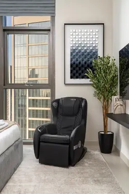 a black reclining chair in a living room with windows at Burj Khalifa Doorstep Stunning 2BR Apartment in Dubai