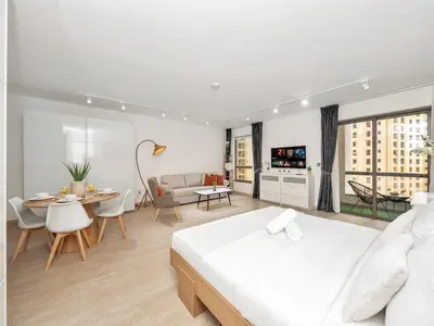 a white bedroom with a bed and a dining room at JBR Studio - Steps to Beach & Marina Walk - Pool & Gym in Dubai