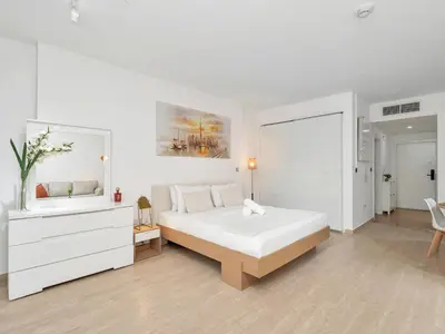 a white bedroom with a large bed and a sink at JBR Studio - Steps to Beach & Marina Walk - Pool & Gym in Dubai