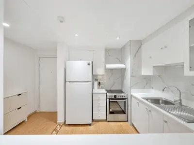 a white kitchen with a refrigerator and a sink at JBR Studio - Steps to Beach & Marina Walk - Pool & Gym in Dubai