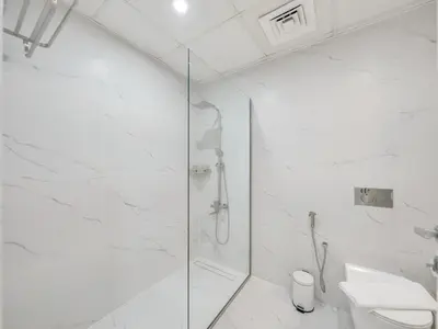 a white bathroom with a shower and a toilet at JBR Studio - Steps to Beach & Marina Walk - Pool & Gym in Dubai