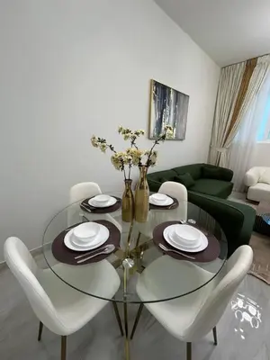 a dining room with a glass table and white chairs at Luxury two bedroom at Gemz in Dubai