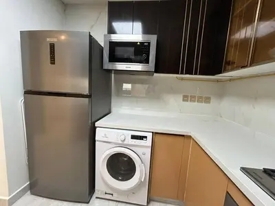 a kitchen with a refrigerator and a washing machine at Luxury two bedroom at Gemz in Dubai