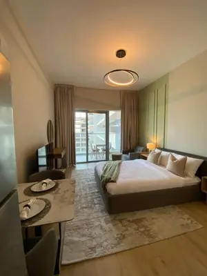 a bedroom with a bed and a table and a room at Bright and Stylish Studio - Azizi Aura in Dubai