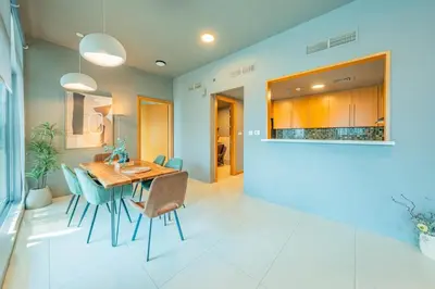 a dining room with a wooden table and blue chairs at Stylish Two-BHK Apartment - Iris Blue, Marsa Dubai in Dubai