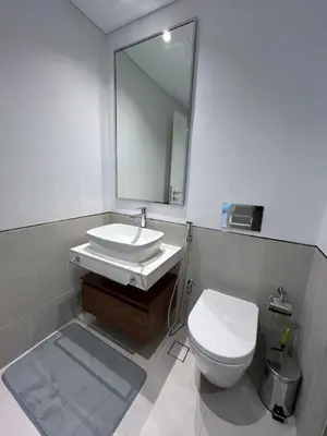 a bathroom with a sink and a toilet and a mirror at Comfortable one bed - Gym and Parking in Dubai