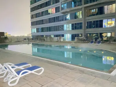 a swimming pool with two lounge chairs and a building at Modern 2BR in Skycourt Tower A - Free Parking - Pool and Gym in Dubai