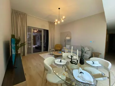 a living room with a glass table and white chairs at Two-Bedroom Apartment with Prime Metro Access in Dubai