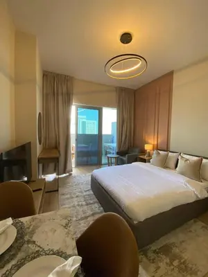 a bedroom with a large bed and a living room at Furnished studio apartment next to metro in Dubai