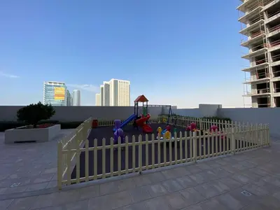 a playground on a rooftop with a white fence at Furnished studio apartment next to metro in Dubai