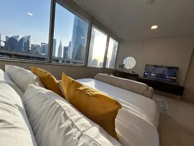 a living room with white furniture and a large window at Elegant Studio in Difc - Skyline Views, Pool, Gym in Dubai