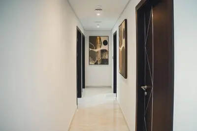 a hallway with black doors and white walls at Fully Furnished 2-Bedroom Apt in Gemz by Danube in Dubai