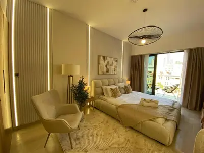 a bedroom with a large bed and a chair at Cozy Studio Apartment with Balcony in Dubai