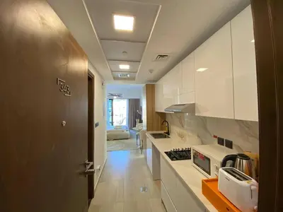 a kitchen with white cabinets and a counter top at Cozy Studio Apartment with Balcony in Dubai