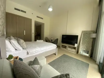 a living room with a bed and a television at Studio Apartment with Pool and Gym Access in Dubai