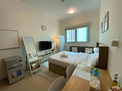 a bedroom with a bed and a table and a television at Charming Studio Apartment in Jadaf in Dubai