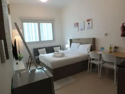 a bedroom with a bed and a table and a desk at Charming Studio Apartment in Jadaf in Dubai