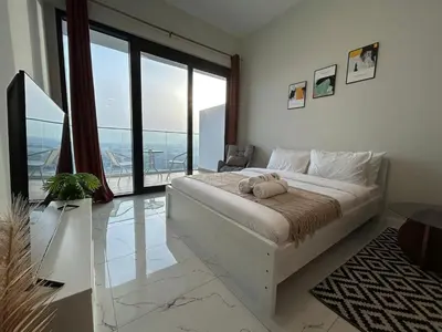 a bedroom with a large bed and a large window at Modern Studio Apt in Jabel Ali Near Metro in Dubai