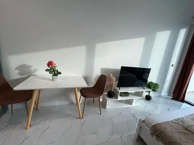 a living room with a white table and a television at Modern Studio Apt in Jabel Ali Near Metro in Dubai