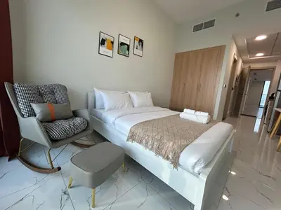 a bedroom with a large bed and a chair at Modern Studio Apt in Jabel Ali Near Metro in Dubai