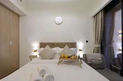 a bedroom with a large white bed with a clock on the wall at Fully Equipped Studio in Meydan in Dubai