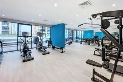 a gym with cardio equipment in a building with windows at Fully Equipped Studio in Meydan in Dubai