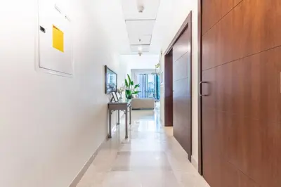 a hallway with a wooden door and a table at Modern and Cozy One BHK Apt - Heart of Downtown Dubai in Dubai