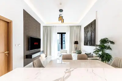 a living room with a dining table and a living room with white walls at Modern 1BR Apt in Azizi Riviera 51 - Pool and Gym in Dubai