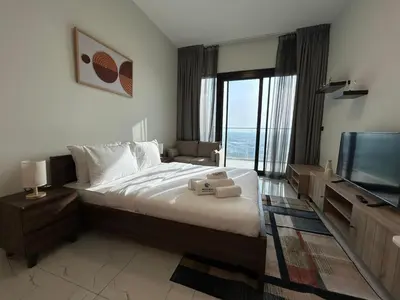 a bedroom with a large bed and a flat screen tv at Modern Studio Apt in Jabel Ali Near Metro in Dubai