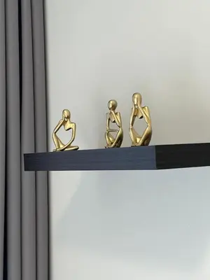 three gold metal objects sitting on a black shelf at Modern Studio Apt in Jabel Ali Near Metro in Dubai