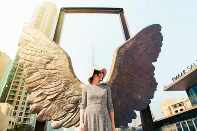 a woman standing in front of an angel wings statue at Highend Luxury 2BR Direct Burj Khalifa & Fountain Views in Dubai