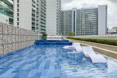 a swimming pool with two white benches on a building at Canal View, Easy Downtown Access, Reva Residences, Business Bay by Deluxe Holiday Homes in Dubai