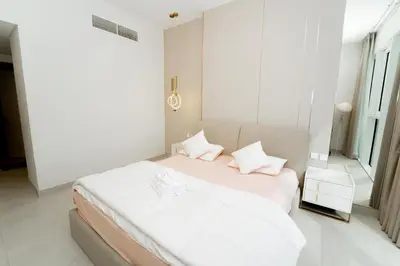 a white bedroom with a bed with white sheets and pillows at Luxury 2BR in Al Kifaf with Frame View, Near Trade Center, Metro Access in Dubai