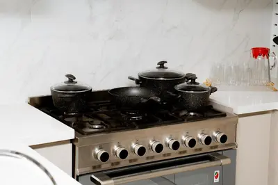 three pots sitting on top of a stove in a kitchen at Luxury 2BR in Al Kifaf with Frame View, Near Trade Center, Metro Access in Dubai