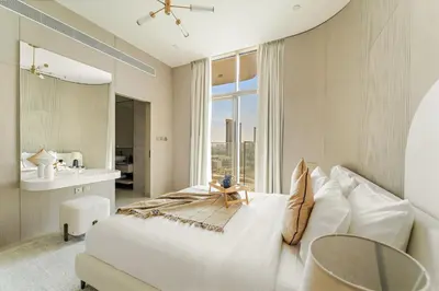 a bedroom with a large white bed and a bathroom at VayK - Contemporary One Bedroom Apartment in JVC in Dubai