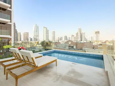 a balcony with a chair and a swimming pool at VayK - Contemporary One Bedroom Apartment in JVC in Dubai