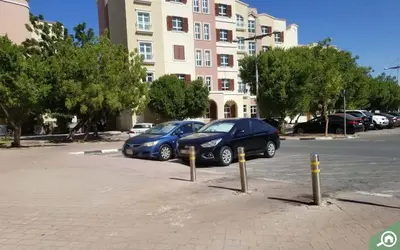 two cars parked in a parking lot in front of a building at Studio in discovery garden Near gardens metro station in Dubai