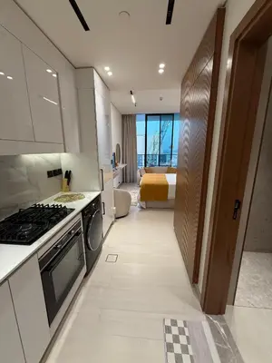 a kitchen with a stove and a bed in a room at Modern Studio Apartment In JVC in Dubai