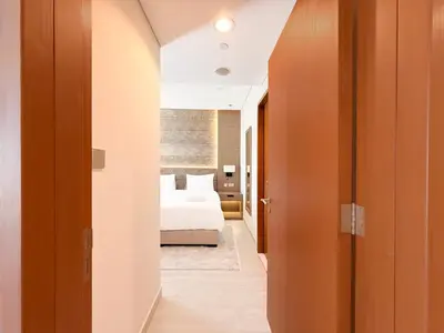 a bedroom with a white bed and a room with a door at Luxurious 1 BR Apt Kempinski Central Avenue in Dubai