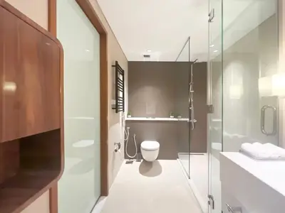 a bathroom with a toilet and a glass shower at Luxurious 1 BR Apt Kempinski Central Avenue in Dubai