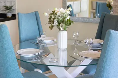 a glass table with plates and a vase with flowers at Damac Maison Mall Street! 2 Bedroom, 2 minute to Dubai Mall! in Dubai