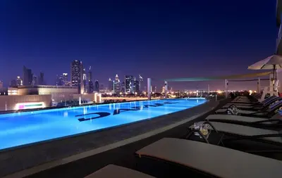a large swimming pool with a city skyline at night at Damac Maison Mall Street! 2 Bedroom, 2 minute to Dubai Mall! in Dubai
