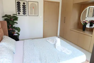 a white towel laying on a bed in a room at Minteh Holiday Home in Dubai