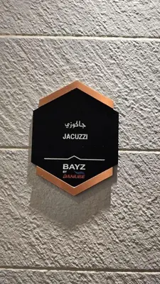 a black sign on the side of a brick wall at Bayz by Danube by That Place Home Living in Dubai