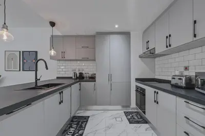 a kitchen with white cabinets and a sink at Beachfront Studio JBR - Murjan 2 by Home Of Choice in Dubai