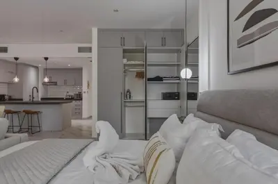 a living room with a bed with pillows and a kitchen at Beachfront Studio JBR - Murjan 2 by Home Of Choice in Dubai